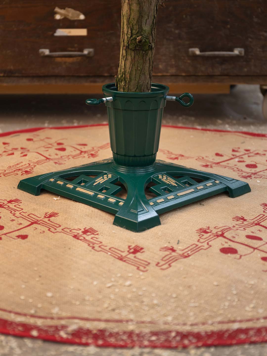 Gr&ouml;n julgransfot i gjutj&auml;rn p&aring; julgransmatta.