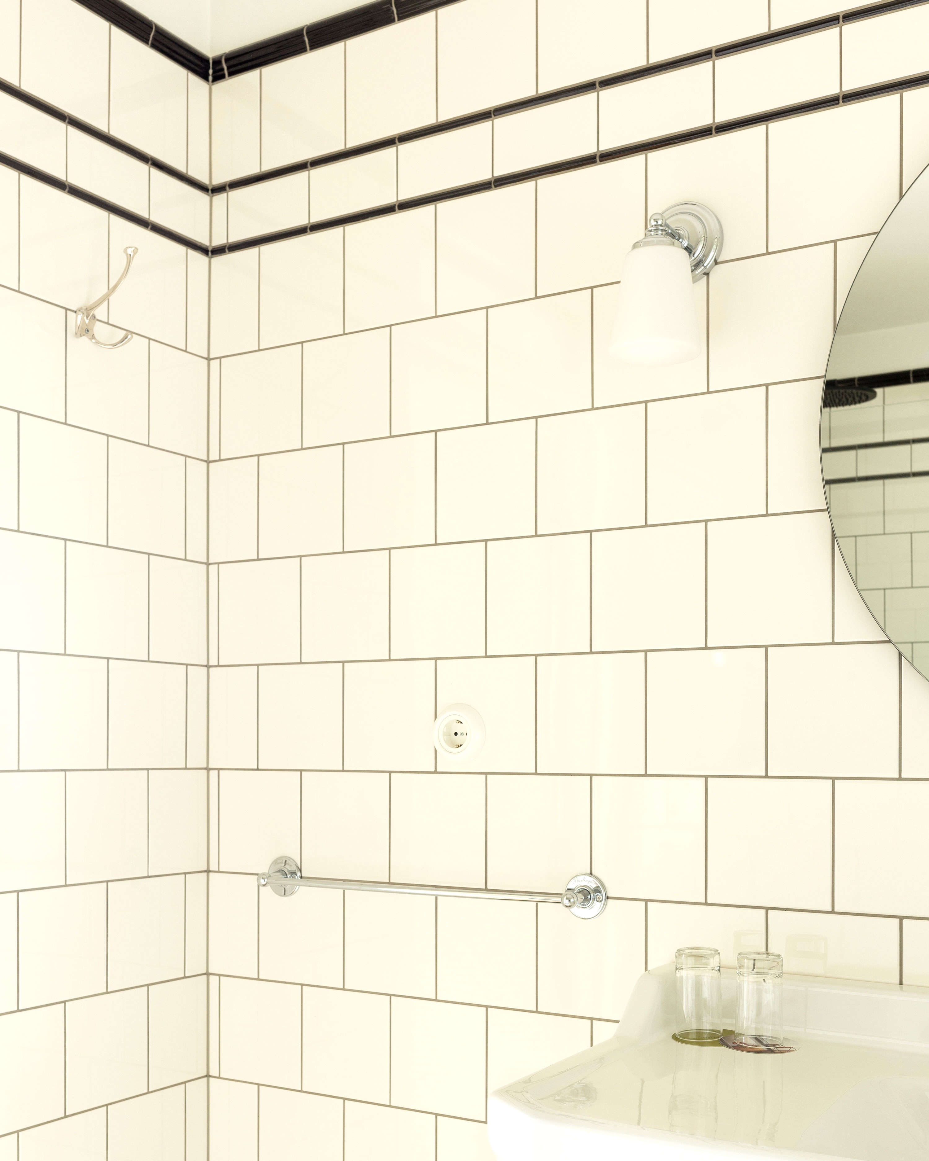 Badrum med vitt kakel p&aring; v&auml;ggarna och svarta kakellister upptill