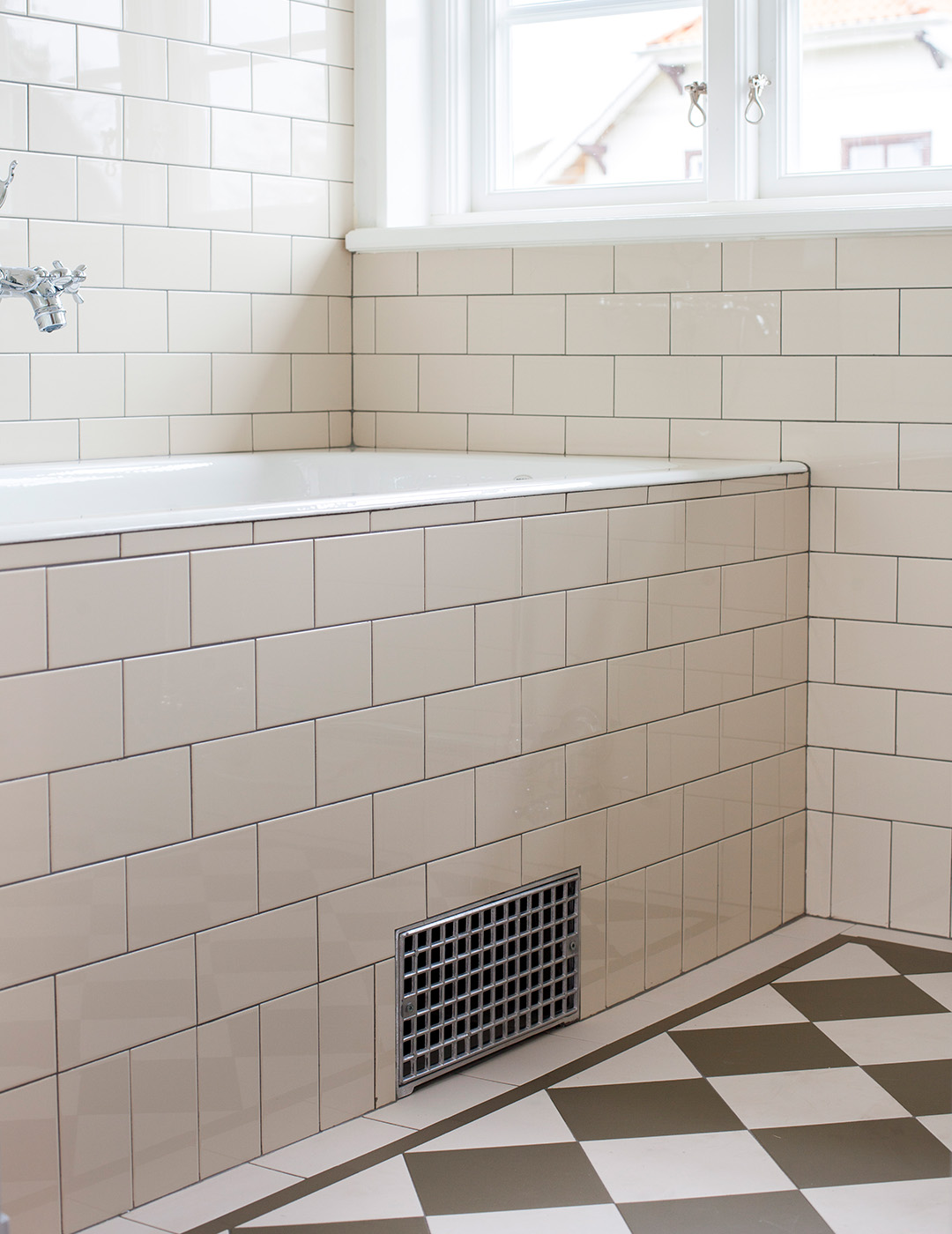 Funkisbadrum med inbyggt badkar med naturvitt kakel i tegelf&ouml;rband. Klinkergolv i vitt och gr&ouml;nt.