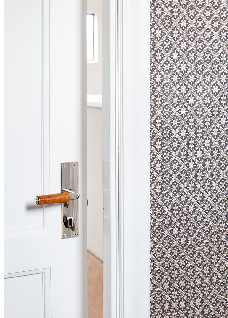 Ett funkishandtag med grepp av teak och l&aring;ngskylt och wc-vred i f&ouml;rnicklad m&auml;ssing.