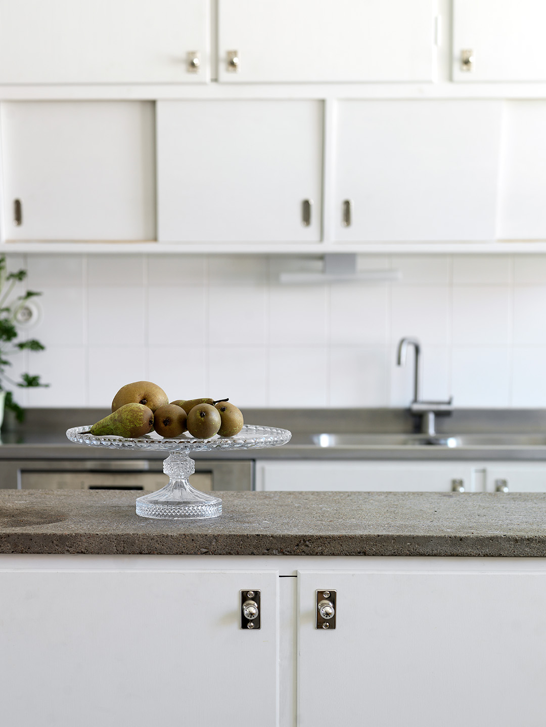 Vitt m&aring;ttbyggt funkisk&ouml;k med snedst&auml;llda luckor undertill &ouml;versk&aring;pen. F&ouml;rnicklade tidsenliga beslag i f&ouml;rnicklad m&auml;ssing. K&ouml;ks&ouml; med betongskiva.