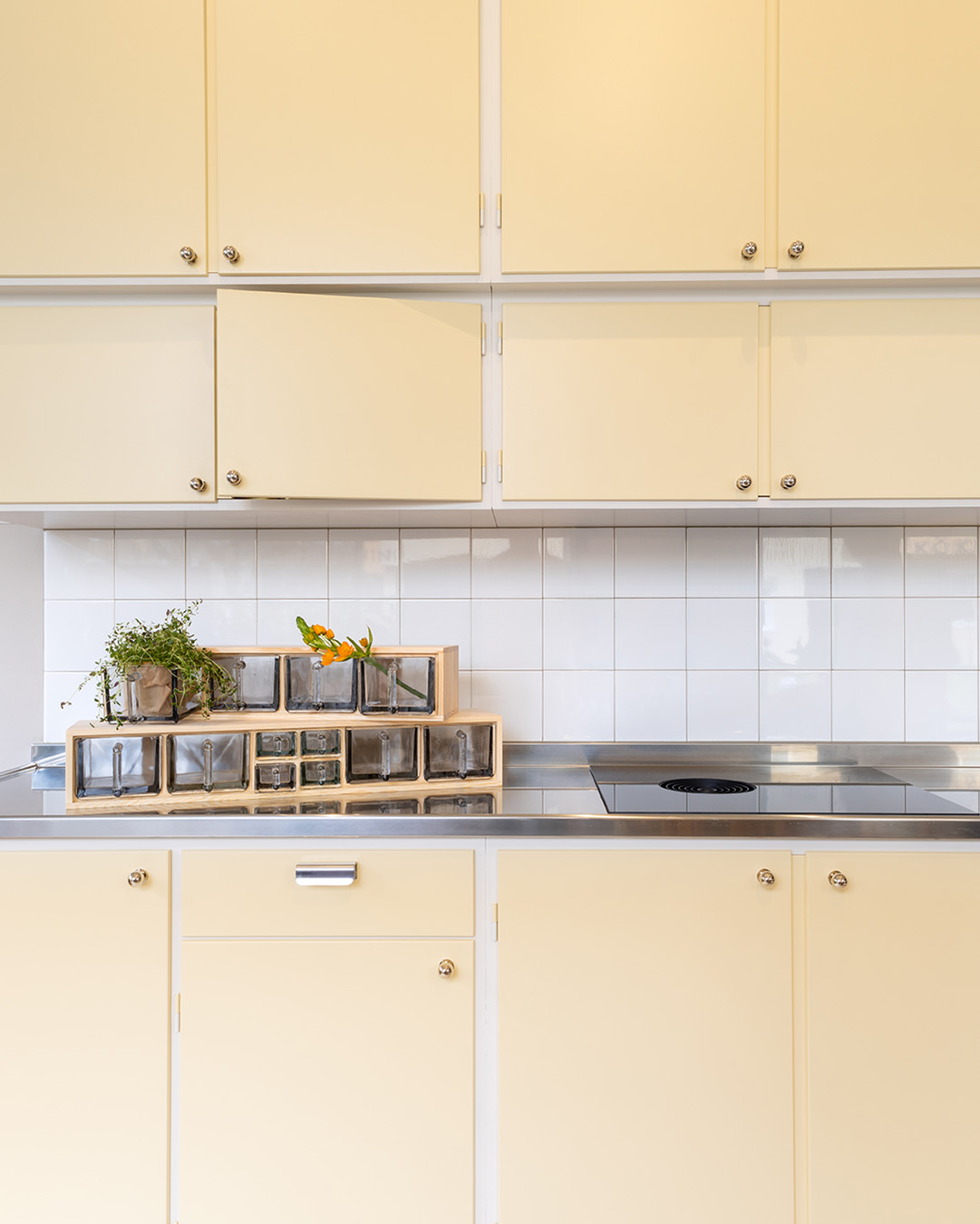 Ljusgult m&aring;ttbyggt k&ouml;k med tv&aring; hyllor med f&ouml;rnicklade Ribershusknoppar.