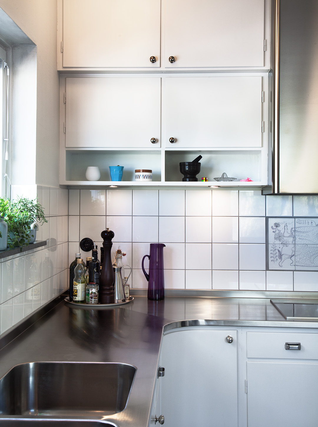 M&aring;ttbyggt k&ouml;k i funkisstil med skarvl&ouml;s b&auml;nkskiva som l&ouml;per &ouml;ver in&aring;tg&aring;ende h&ouml;rn. &Auml;ven undersk&aring;pen f&ouml;ljer samma form.