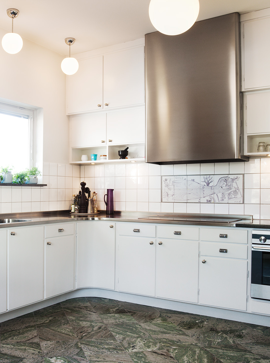 Funisk&ouml;k i vitt med klotlampor i taket och kolm&aring;rdsmarmor p&aring; golvet.