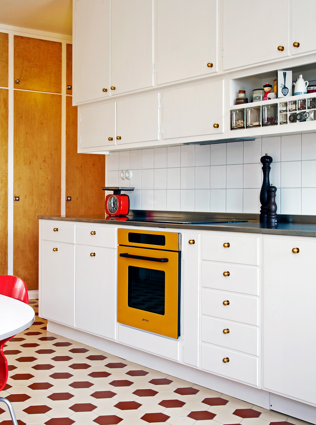 Funkisk&ouml;k i vitt med r&ouml;tt och vitt klinkergolv av hexagonformade plattor.