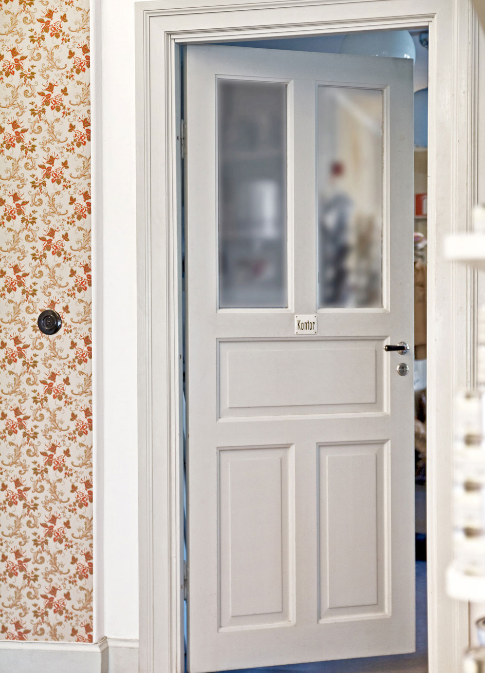 Spegeld&ouml;rr med inf&auml;llt glas och en tapetserad v&auml;gg med blommor i r&ouml;da toner