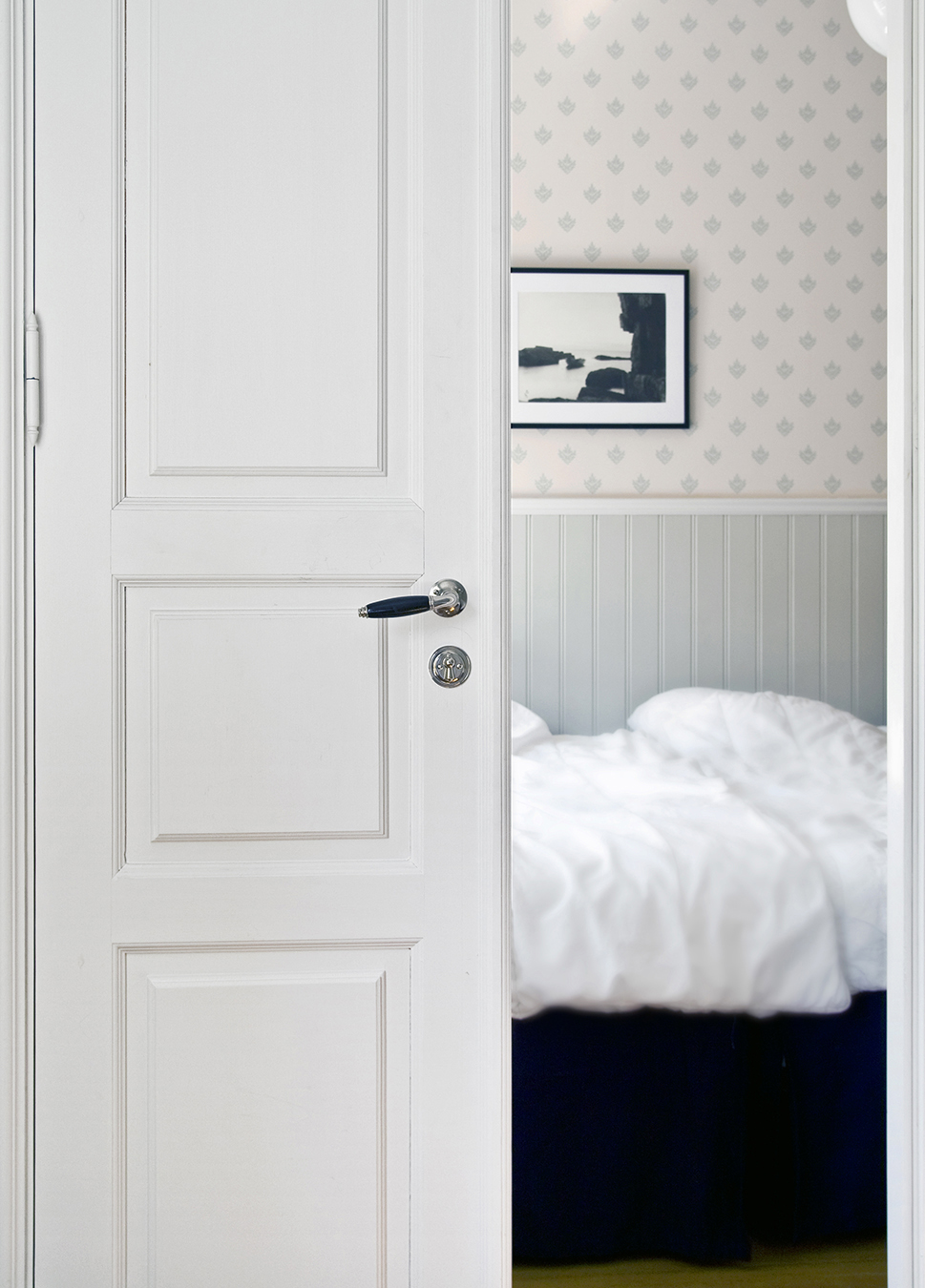 Klassiskt 20-tals handtag Rand p&aring; en ljusgr&aring; spegeld&ouml;rr in mot sovrum.