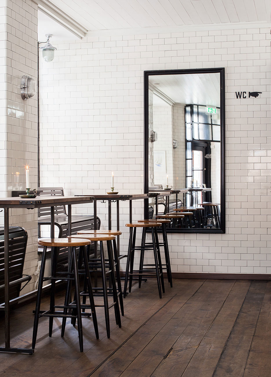 H&ouml;rn i restaurang med h&ouml;ga pallar och kaklade v&auml;ggar i vitt h&ouml;gblankt kakel.