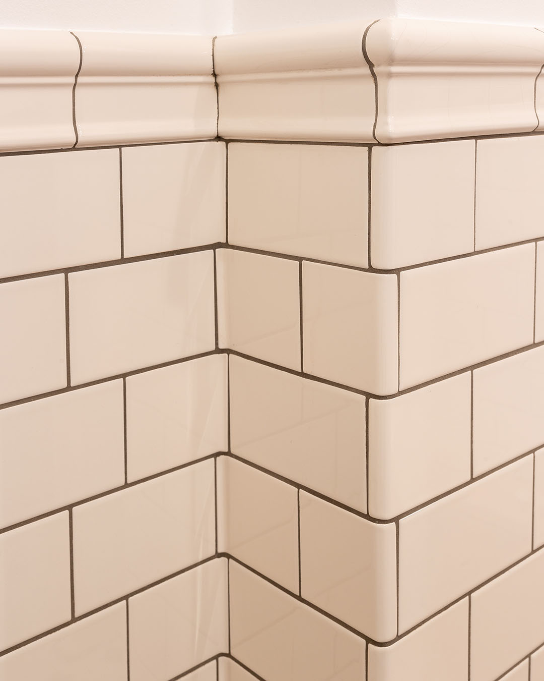 Kaklad v&auml;gg med in&aring;tg&aring;ende och ut&aring;tg&aring;ende h&ouml;rn och avslutande profilerade plattor.