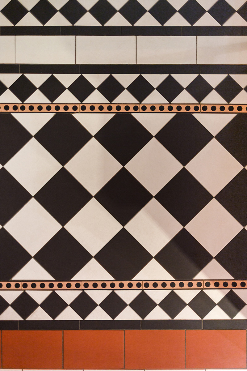 Ett klinkergolv lagt i flera olika rutm&ouml;nster med m&ouml;nstrade b&aring;rder och enf&auml;rgade ramar i svart, vit och r&ouml;d.