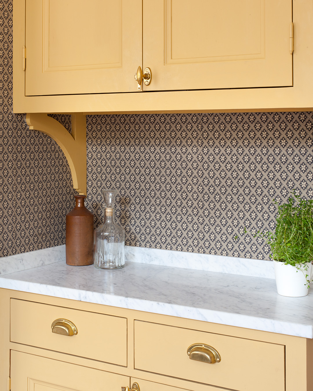 Beslag i obehandlad m&auml;ssing p&aring; sk&aring;p och l&aring;dor i ett k&ouml;k m&aring;lat med linoljef&auml;rg i kul&ouml;ren Varmgul.