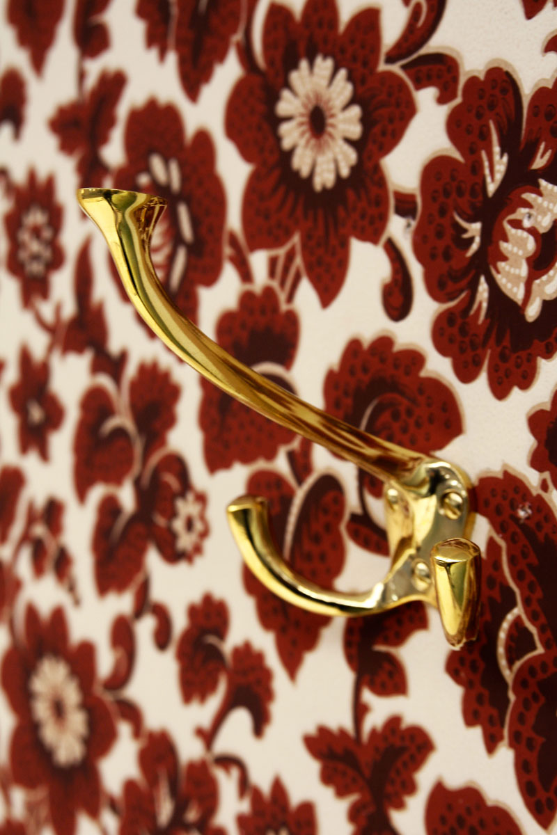 Tapet med djupr&ouml;da blommor och en m&auml;ssingskrok