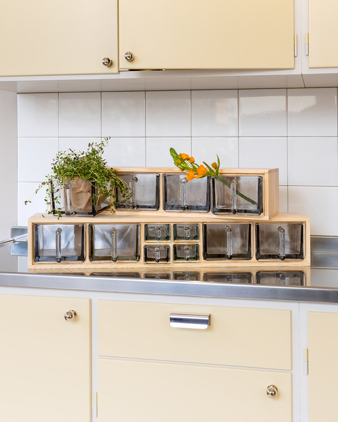 Ljusgult m&aring;ttbyggt k&ouml;k med tv&aring; hyllor med glask&auml;ppor.