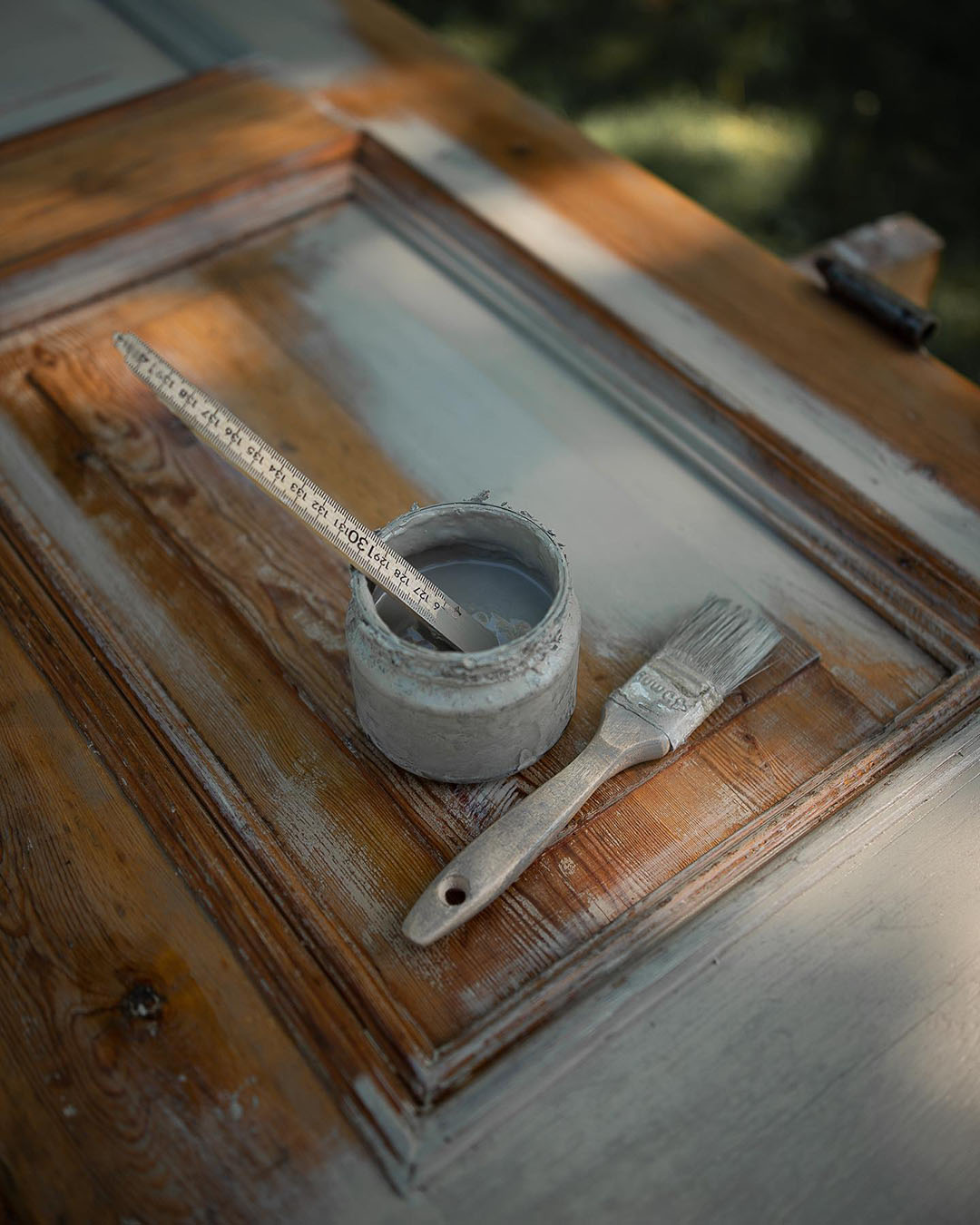 Linoljef&auml;rg och pensel p&aring; en halvm&aring;lad yta av tr&auml;.