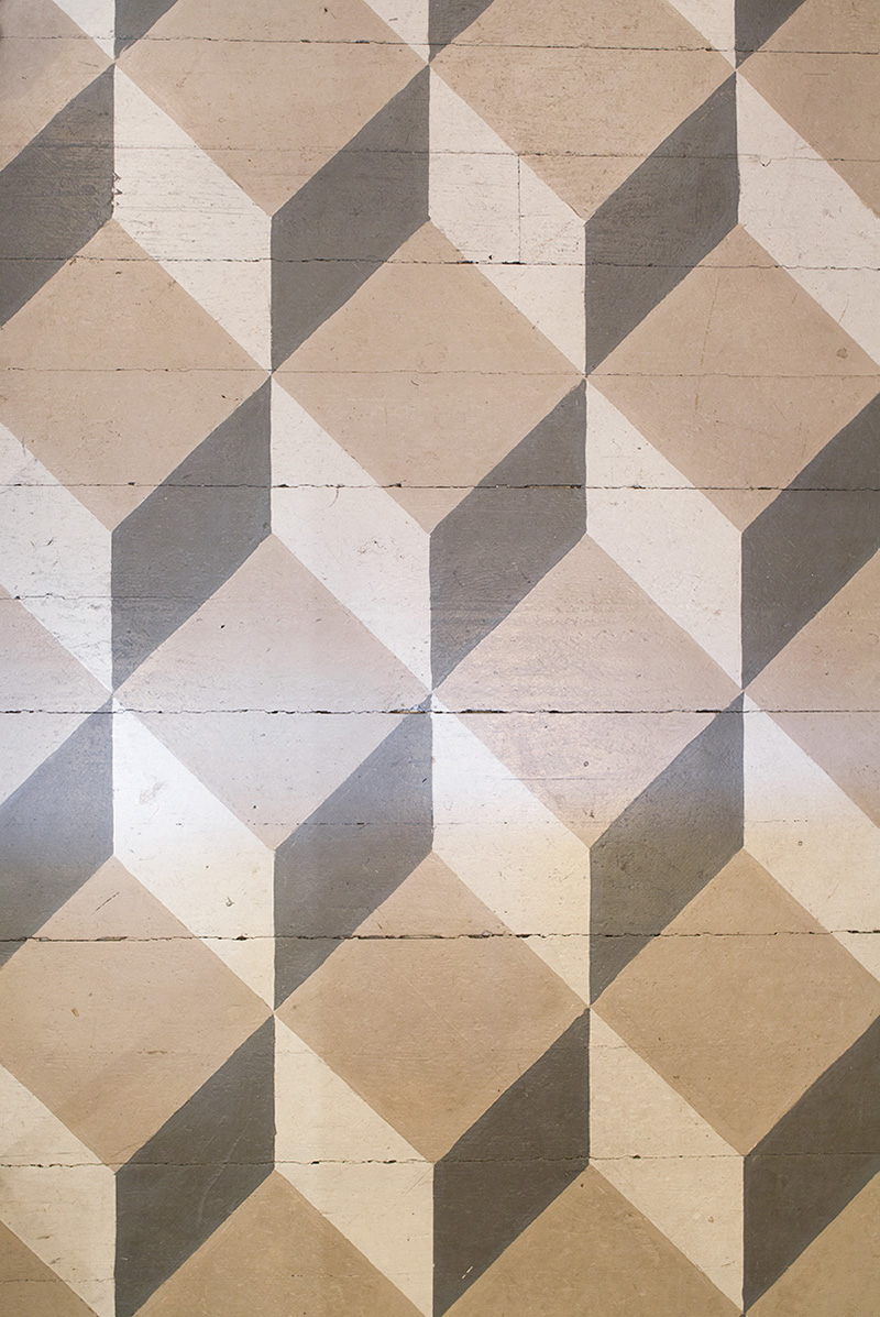 Ett gammalt br&auml;dgolv av furu som m&aring;lats med linoljef&auml;rg i ett rutm&ouml;nster i bruna och gr&aring; toner.