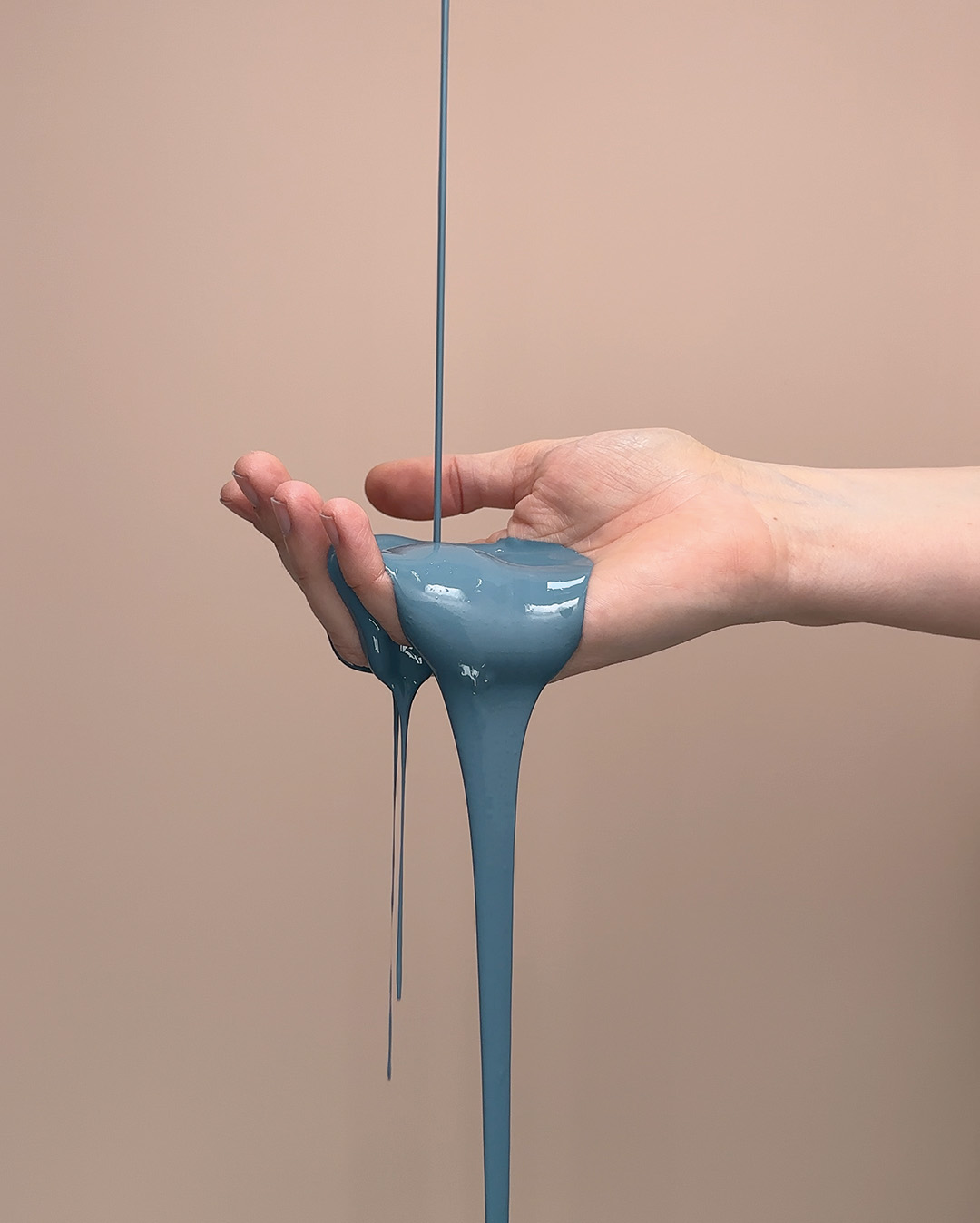 Bl&aring; f&auml;rg rinner ner i en &ouml;ppen hand mot en rosa bakgrund.