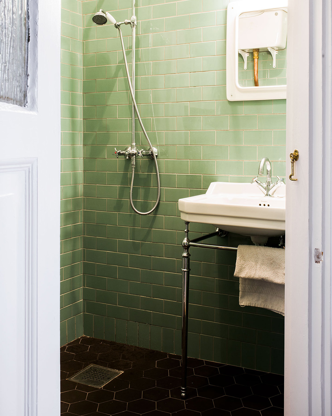 Badrum i sekelskiftesstil med gr&ouml;nt kakel i half tileformat.
