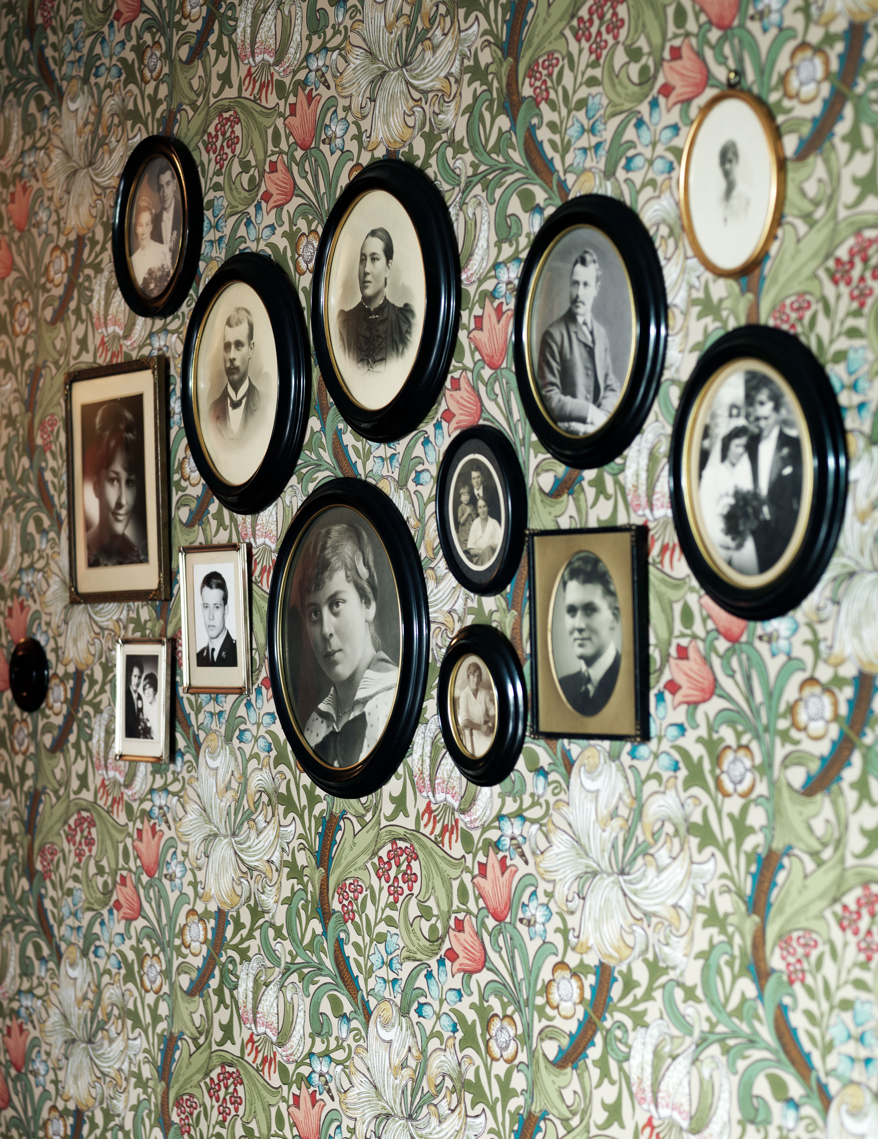 Tavelv&auml;gg med gamla svartvita foton p&aring; m&ouml;nstrad tapet