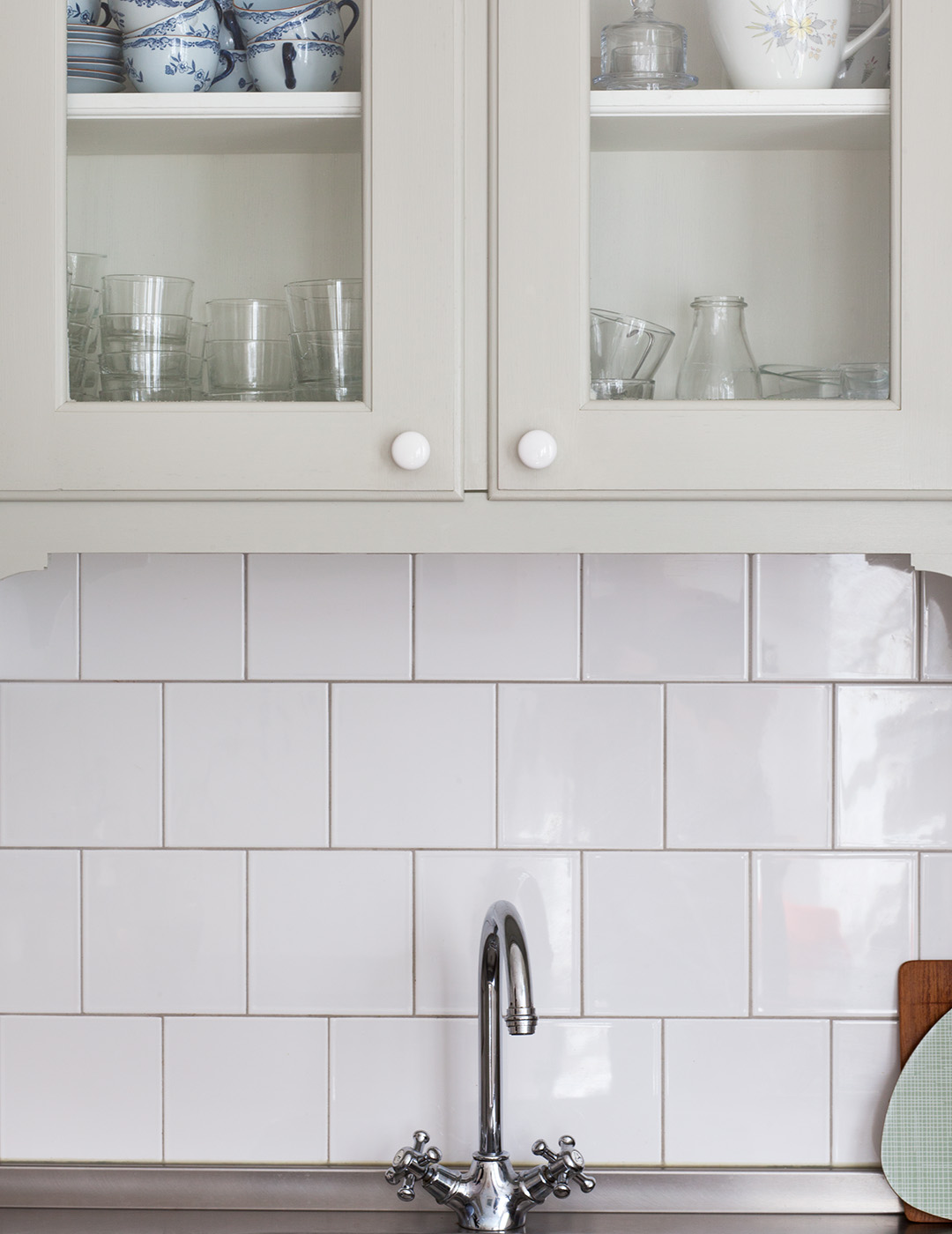 M&aring;ttbyggt k&ouml;k i tjuotalsstil m&aring;lat i ljust gr&aring;gr&ouml;n linoljef&auml;rg. Luckorna har inf&auml;llt glas och v&auml;ggen &auml;r kaklad med vita kvadratiska plattor.