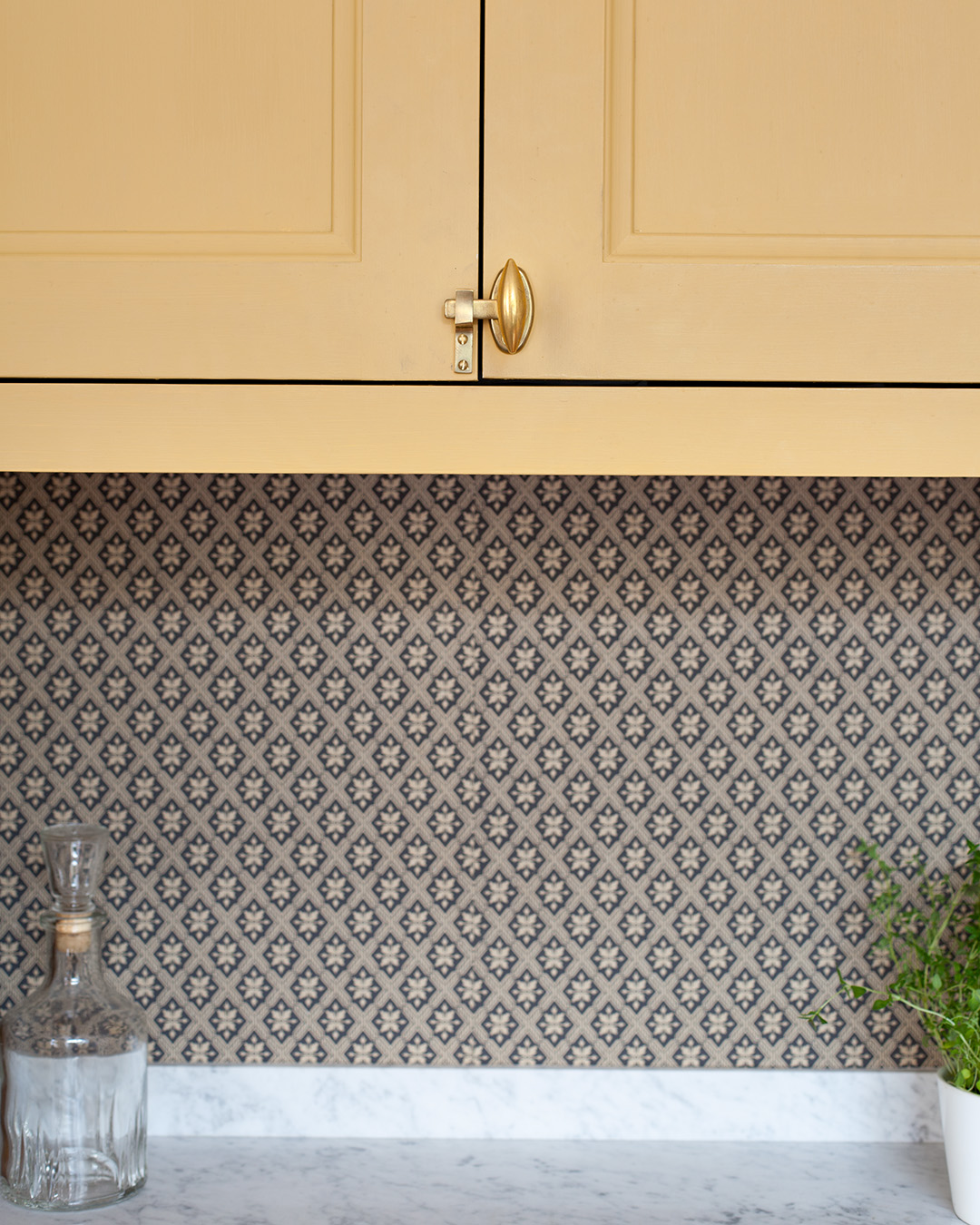 Beslag i obehandlad m&auml;ssing p&aring; sk&aring;p och l&aring;dor i ett k&ouml;k m&aring;lat med linoljef&auml;rg i kul&ouml;ren Varmgul.